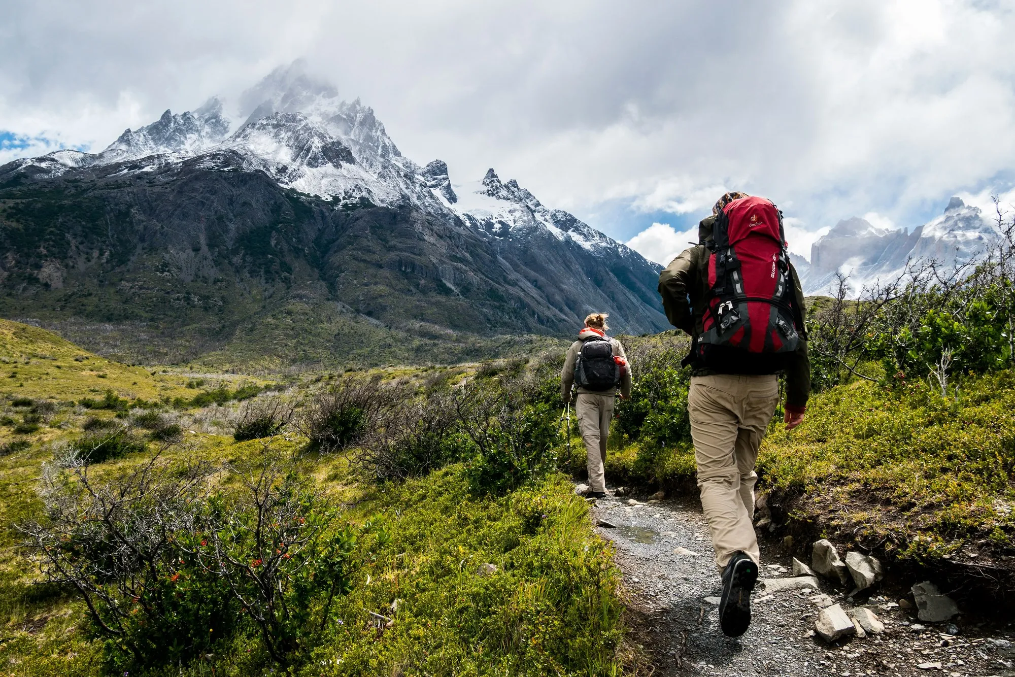 Hikers on a trail toward snow-capped Himalayan peaks